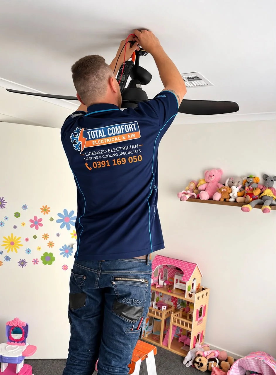 Total Comfort electrician working on a black ceiling fan